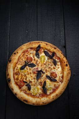 Tahta bir masada peynirli ve sebzeli lezzetli bir pizza.