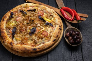 Tahta bir masada peynirli ve sebzeli lezzetli bir pizza.