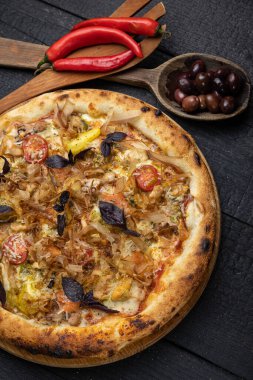Tahta bir masada peynirli ve sebzeli lezzetli bir pizza.