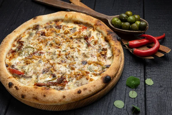 stock image tasty pizza with cheese and vegetables on a wooden dark table