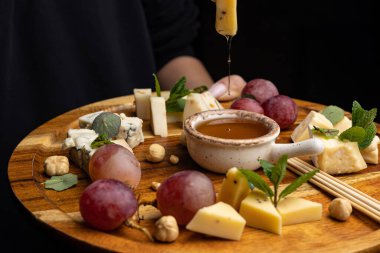 Peynir tabağı: Camembert, Parmesan peyniri, fındık, bal ve üzümlü mavi peynir.