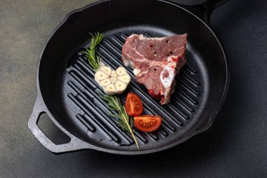 Dökme demir tavada baharatlı çiğ biftek.
