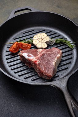 Dökme demir tavada baharatlı çiğ biftek.