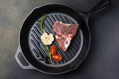 Dökme demir tavada baharatlı çiğ biftek.