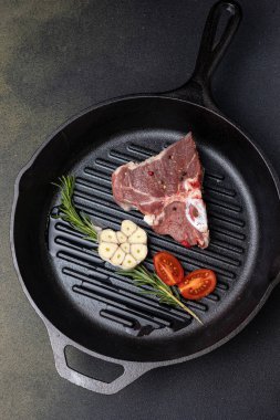 Dökme demir tavada baharatlı çiğ biftek.