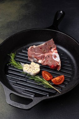 Dökme demir tavada baharatlı çiğ biftek.