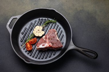 Dökme demir tavada baharatlı çiğ biftek.