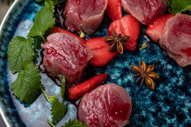 Mavi tabakta baharatlı çiğ et parçaları.