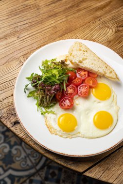 a delicious breakfast on a plate prepared in the restaurant. Fried eggs with tomatoes and salad