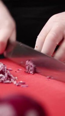 Şef kırmızı tahtada soğan doğruyor.