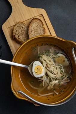 Tahtada iki parça ekmek olan bir kase çorba..