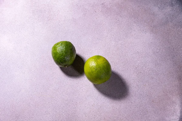 Pair Limes Sit Purple Surface — Stock Photo, Image