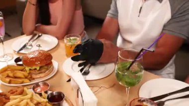 Bir kafede fast food. Yakın plan. Bir adam hamburger yiyor.