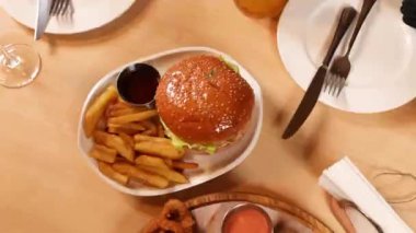 Bir kafede fast food. Yakın plan. Bir adam hamburger yiyor.