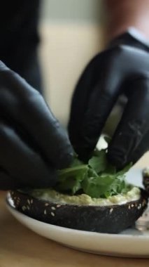  Siyah eldivenli şef karidesli bir hamburger hazırlar.