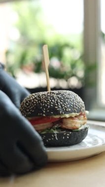  Siyah eldivenli şef karidesli bir hamburger hazırlar.