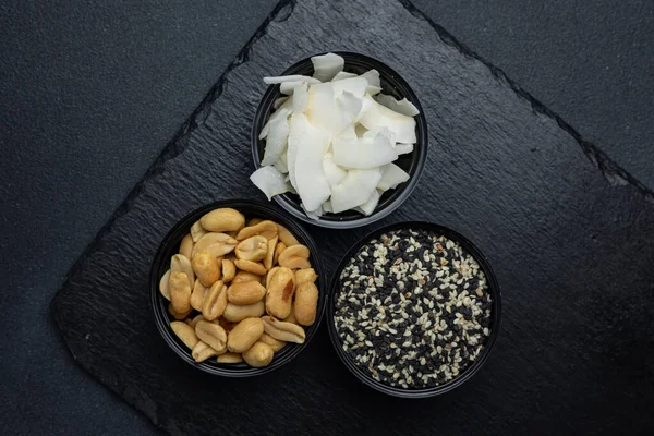 sesame, coconut and nuts on a black background.  Close up