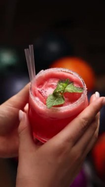 Bir kız kırmızı kokteyl tutuyor. Yakın plan. 