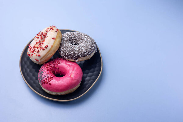 Delicious donuts in a plate on a blue background