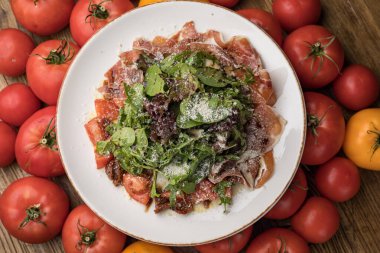 Parmesanlı lezzetli salata, jambon, beyaz tabakta domates. 