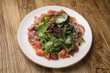 Parmesanlı lezzetli salata, jambon, beyaz tabakta domates. 