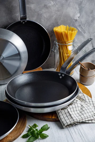 Mutfakta tencere ve tavalar, gri bir arka planda.