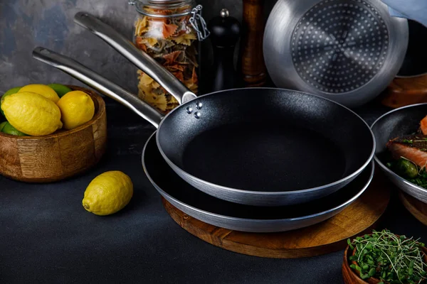 Mutfakta tencere ve tavalar, gri bir arka planda.