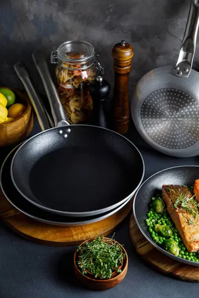 Mutfakta tencere ve tavalar, gri bir arka planda.