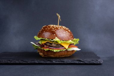 Pirzola, marul, domates, soğan, sos ve yakın çekim ile nefis bir hamburger.