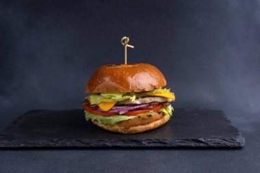 Pirzola, marul, domates, soğan, sos ve yakın çekim ile nefis bir hamburger.