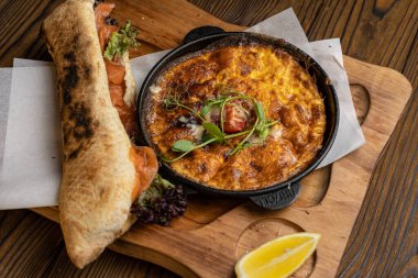 Tahta bir masa ve sandviçle domatesli, sebzeli lezzetli bir omlet. 