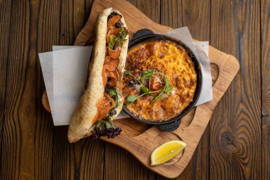 Tahta bir masa ve sandviçle domatesli, sebzeli lezzetli bir omlet. 