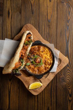 Tahta bir masa ve sandviçle domatesli, sebzeli lezzetli bir omlet. 