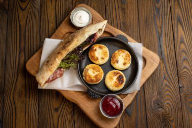 Lezzetli kahvaltı - ekşi kremalı peynirli kekler ve ahşap bir masada reçel. 