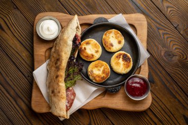 Lezzetli kahvaltı - ekşi kremalı peynirli kekler ve ahşap bir masada reçel. 