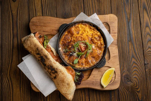 Tahta bir masa ve sandviçle domatesli, sebzeli lezzetli bir omlet. 