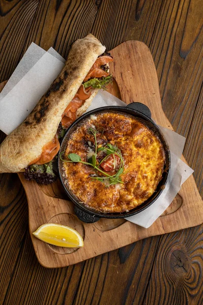 Tahta bir masa ve sandviçle domatesli, sebzeli lezzetli bir omlet. 