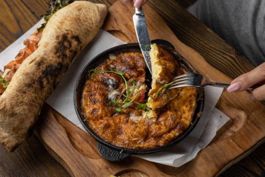 Tahta bir masa ve sandviçle domatesli, sebzeli lezzetli bir omlet. 