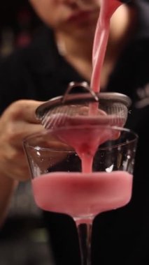 Bir barmen barda alkollü bir kokteyl hazırlar. Kapat.