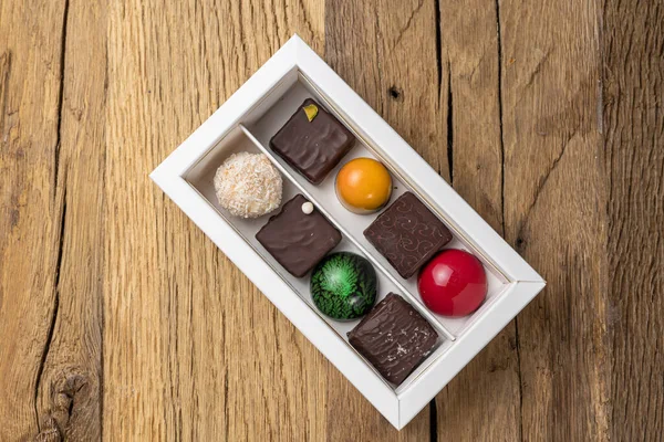 Assorted sweets in a box on a wooden table