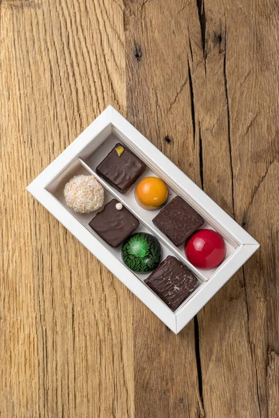 Assorted sweets in a box on a wooden table