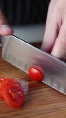 Şef ahşap bir tahtada domatesleri dilimliyor.