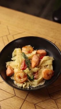 Genç bir bayan restoranda deniz mahsulleriyle makarna yiyor.