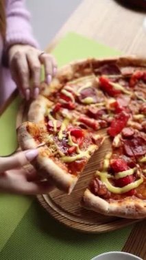Şef sosisli, peynirli, domatesli pizza pişirir.