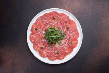 Yuvarlak tabakta taze et ve roka ile taze carpaccio.