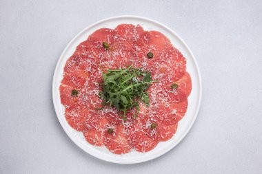 Yuvarlak tabakta taze et ve roka ile taze carpaccio.