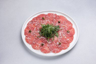 Yuvarlak tabakta taze et ve roka ile taze carpaccio.