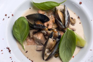 Tabakta bir tabak midye ve fesleğen. Kapat. 