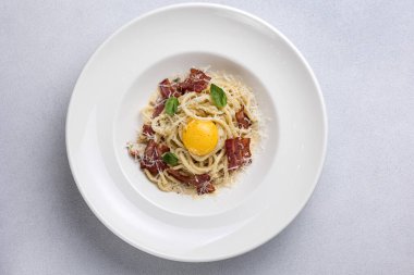 Pastırmalı spagetti ve beyaz tabakta parmesan peyniri.