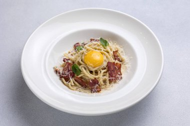 Pastırmalı spagetti ve beyaz tabakta parmesan peyniri.